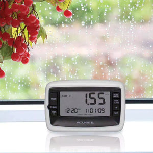 Acurite digital rain gauge monitor on windowsill during rainy weather